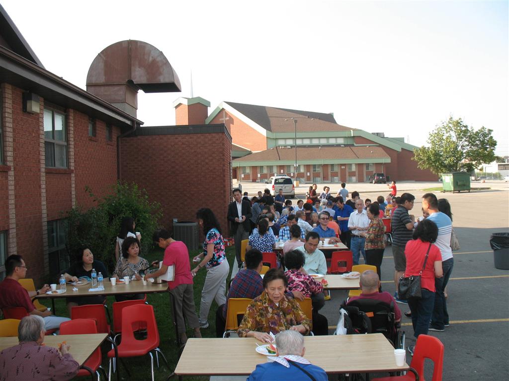 The congregants at Hakka Alliance enjoy a BBQ in the church parking lot after the service.